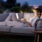 Woman browsing online on a laptop in the evening outdoors, illustrating later consumer behaviour during British Summer Time