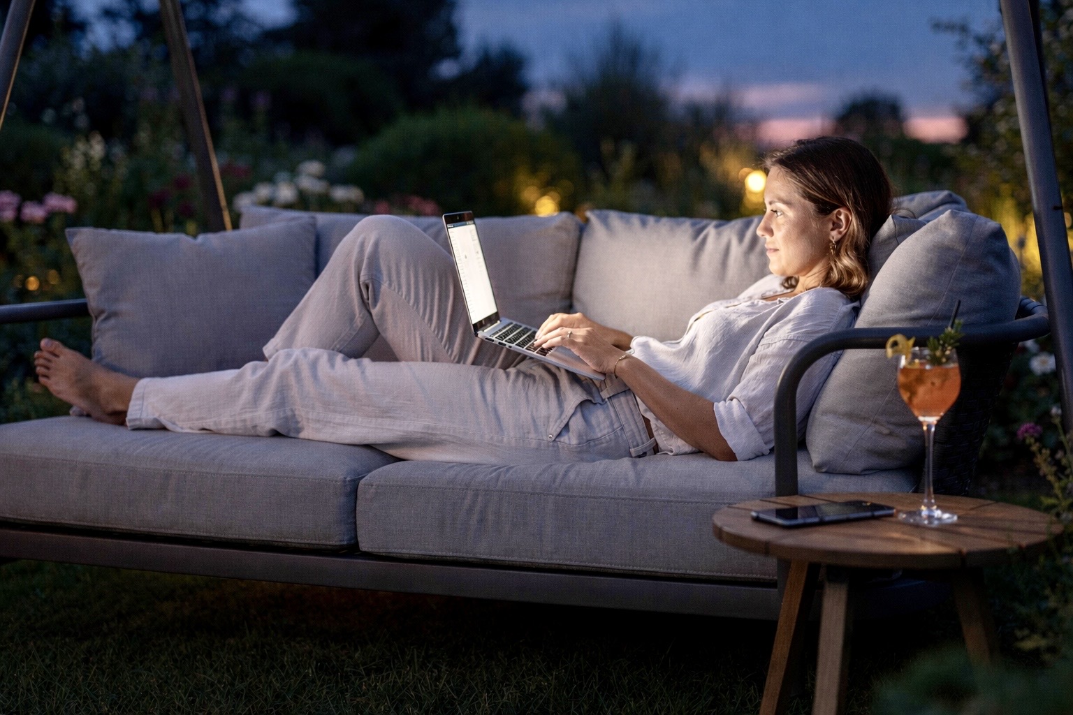 Woman browsing online on a laptop in the evening outdoors, illustrating later consumer behaviour during British Summer Time