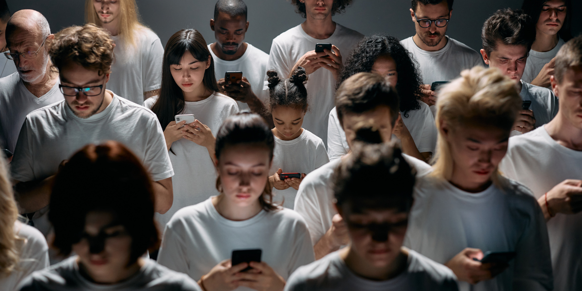 A diverse crowd of adults and children dressed in white, all looking down at their smartphones, illustrating society's dependence on social media.